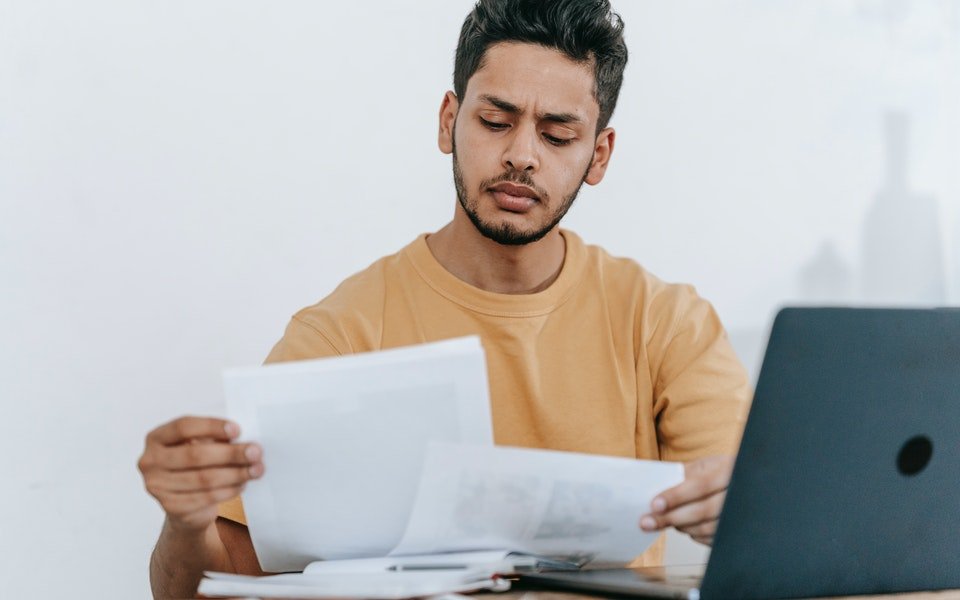 Mahasiswa membaca pedoman penulisan artikel jurnal di laptop